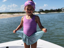 child smiling holding sheer purple skirt on fishscale bathing suit wearing unicorn mermaid neck gaiter headband