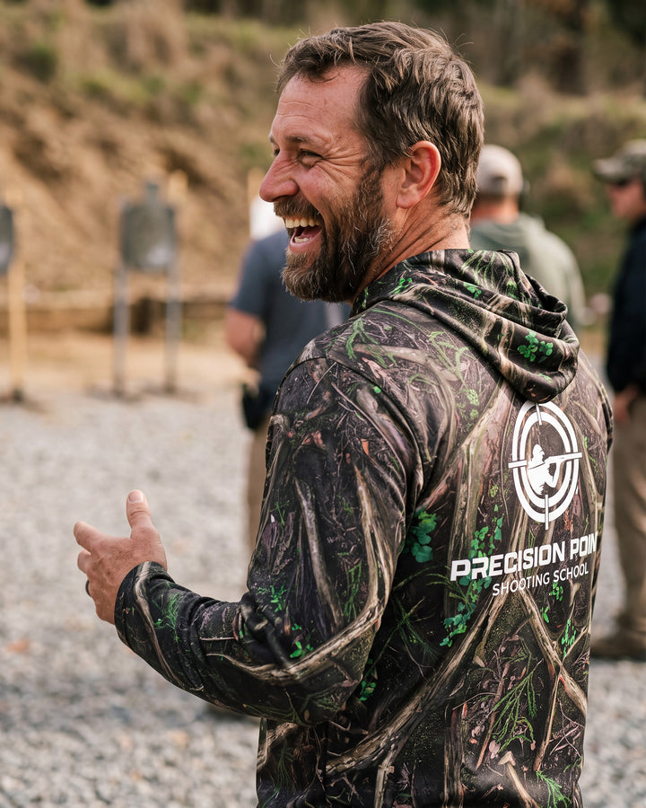 Man at a shooting range, wearing a custom camo hooded cut and sew shirt