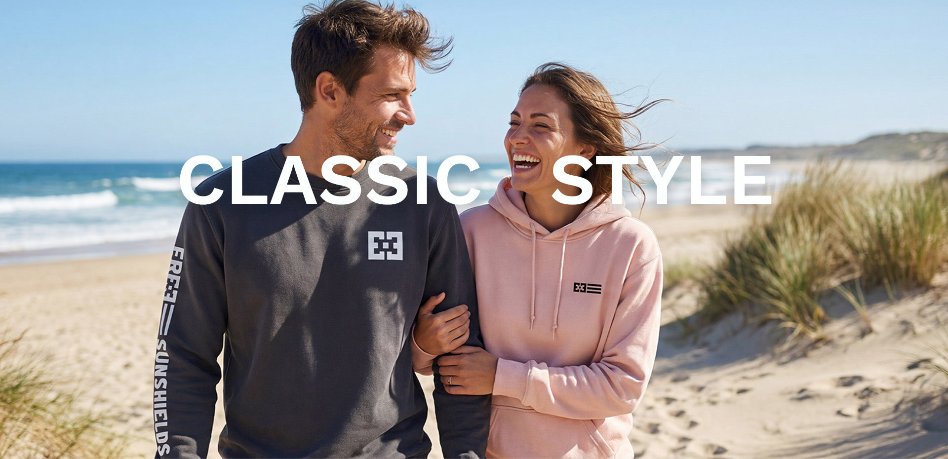 Couple laughing on the beach wearing custom sweatshirts