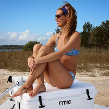 woman sitting on boat in sand wearing free spirit neck gaiter headband