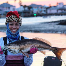 sunset ice fishing woman holding fish wearing waves neck gaiter mask