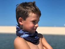 boy on blue ocean beach wearing shark bait neck gaiter scarf