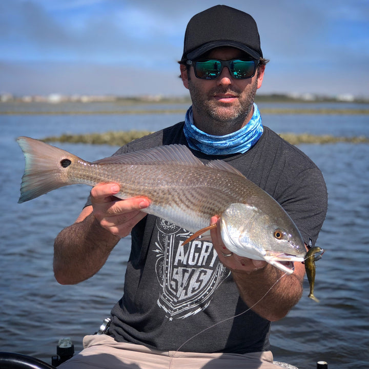 man with grey fish with lure in free sunshields hat sunglasses blue scales neck gaiter mask scarf